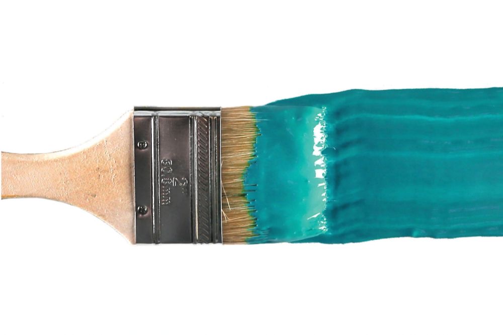 A paintbrush with aqua blue paint on it