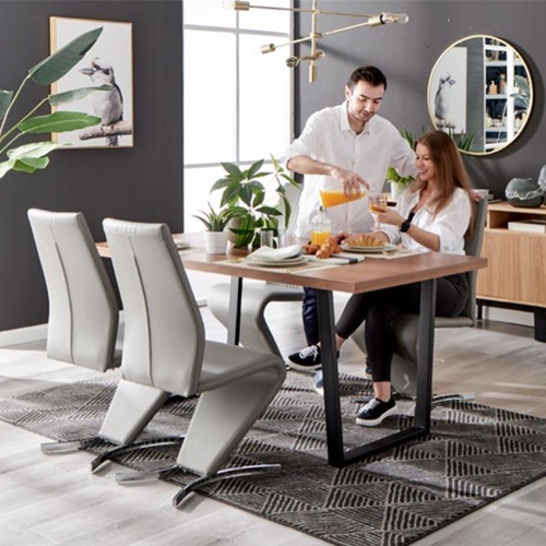 modern dining room with dark grey walls, light grey floor, patterned grey rug, wooden table with black structureal elgs, 4 grey leather chairs, man and woman enjoying brealfast. 