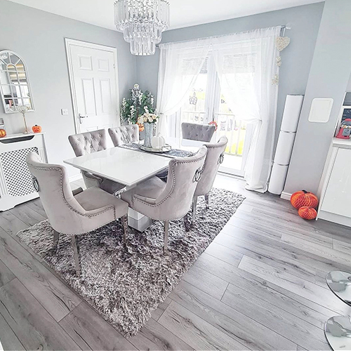 instagram image showing light grey modern dining room  with wood floor and grey rug beneath dining table