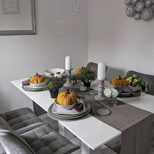 instagram image showing modern dining area - white high gloss dining table with pretty tablescape - hessian jute table runner and yellow napkins folded to look like pumkins