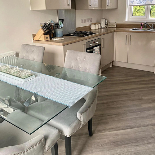 instagram image showing modern dinign area - utty grey cabinets and flooring, glass table and grey velvet chairs