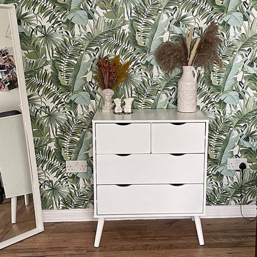 modern room / hallway with botanical print wallpaper and warm wood flooring. White Alma chest of drawers agains the wall, with ceramic vases and ornaments on top, with dired grasses. Positioned beside a tall white-framed mirror.