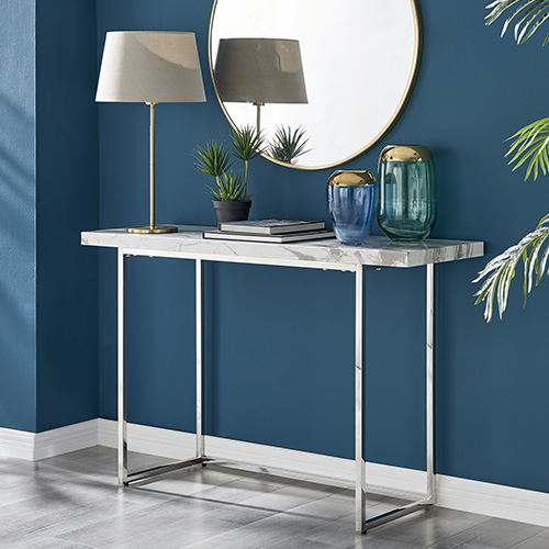 modern hallways - navy wall with pale wood flooring, Kylo marbel-effect tp console table with thin chrome legs, and round wall mirror with thin gold frame behind. Console table has a slender gold-stem table lamp on it. 