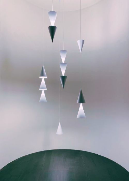 abstract pendant light fixing featuring small hanging cones in white and grey against white wall. 