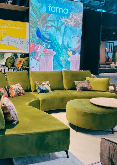 green velvet curved sofa with coloured patterned cushions, and matching round footstool with wooden coffee table slotted over footstool - interior design trends 2023