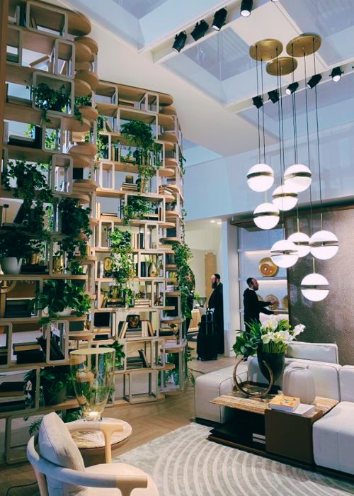 tall shelving used as room divider, with books and planting, beside living room set up and hanging pendant lights