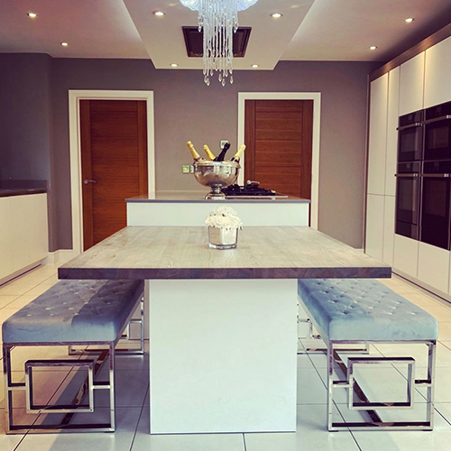 modern open plan kitchen - diner with central island table and 2 bench seats. 