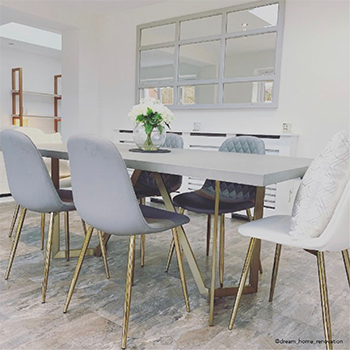 bright white dining area, with modern grey trestle table and 6 faux-leather dining chairs. A mirror is on the far wall, in a frame that makes it look like window panels, and it reflects a door and window/garden opposite.