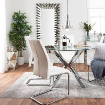 open plan living mirror ideas - a round glass dining table with silver chrome legs and white dining chairs, on a grey rug, on light wooden floor. In the background, a floor-lenght rectangular mirror, 2 potted plants, and a mirrored geometric design side table. 