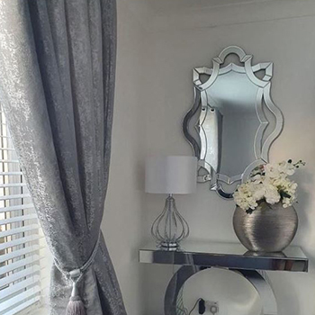 mirror ideas for dark corners - chrome console table with lamp and vase of flowers in shady living room corner, with rectangular mirror hanging above. 