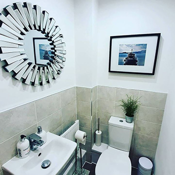 Family bathroom mirror ideas - bathroom with nautical artwork and round mirror in mirrored starburst frame.