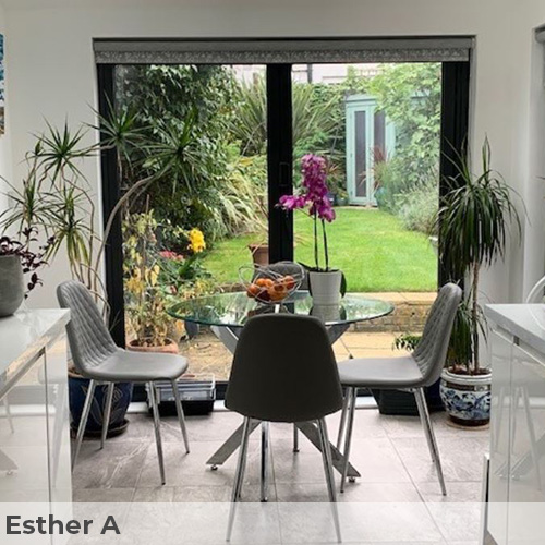 Customer image from Esther A. Bright kithcne-diner area. Tal french windows overlooking lush garden, with many pot plants inside too. White counters and walls. Textured granite effect floor tiling beneath round glass and chrome dining table and 4 grey faux leahter chairs. 