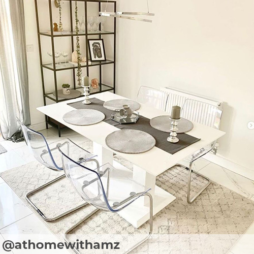 IG imge from @athomewithamz featuring bright light dining area, pale marble effect tiling and beige textured rug under white high gloss dining table.