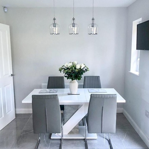 modern dining area with round glass dining table and silver chrome dining table and 4 grey velvet chairs