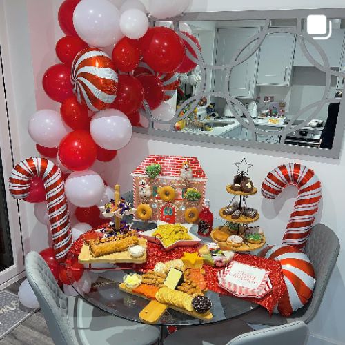 round glass dining table decorated in sweets and cakes, with candy cane balloons 