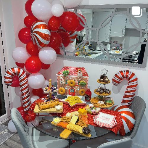 round glass dining table decorated in sweets and cakes, with candy cane balloons 