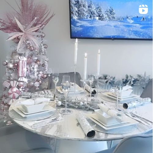 christmas decor inspiration- white and grey dining area featuring round marble effect pedestal table, 4 grey vevlet chairs, pink silver and white christmas tree behind. 