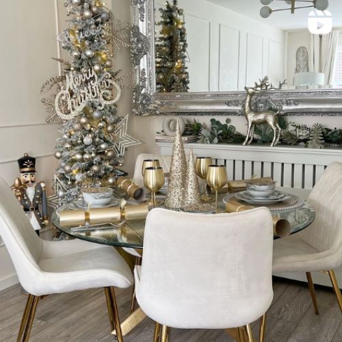 gold and cream dining room dressed for christmas with round glass dining table and white velvet chairs with gold legs