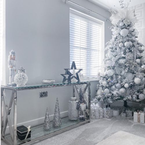 grey living room with grey, silver and white christmas tree, glass and chrome console table.