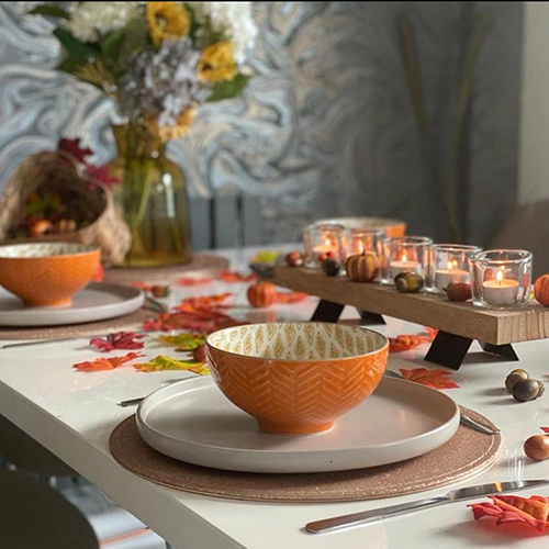 table decorated with autum theme - leaves, orange candlges and orange crockery