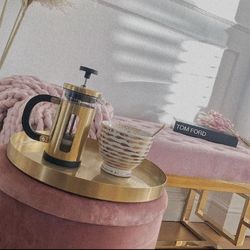 pink velvet statement bench on gold chrome art deco geometric frame legs placed in shallow alcove, with pink stool and gold tray with gold caffetiere in foreground.