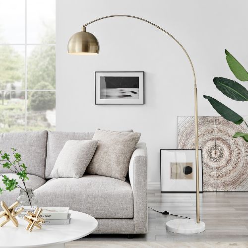 autumn lighting trends: floor standing lamp - gold metal arc lamp with round bowl lampshade on round marble stand, with living room in background