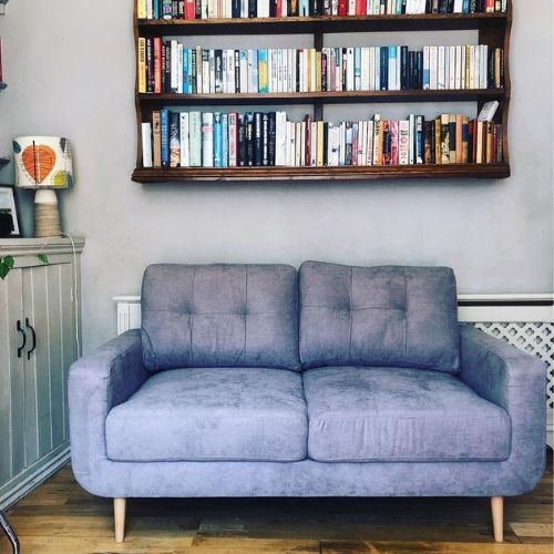 cosy modern minimalist grey fabric sofa below wooden bookshelves