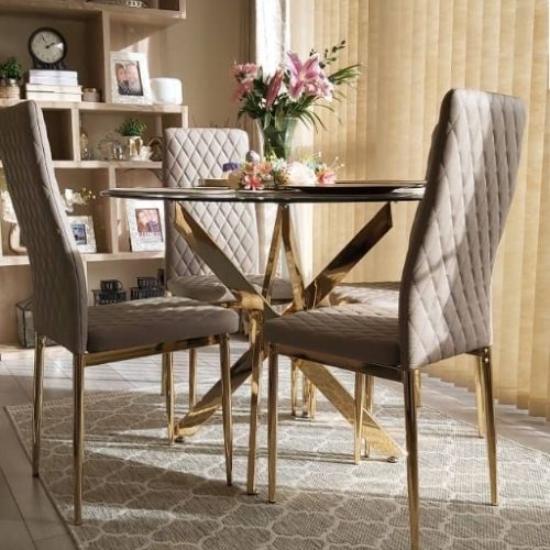 sunny dining area featuring round glass and gold metal dining table, 4 grey faux leather tall back dining chairs and a grey and cream rug with Moroccan lattice pattern.