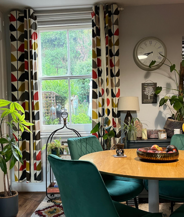 dopamine decor in a boho scandi dining space with round wooden table and green velvet dining chairs