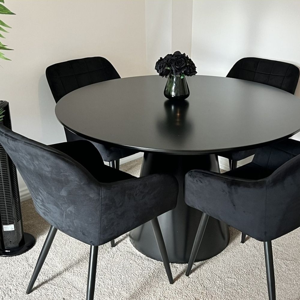 round black semi-gloss pedestal table with 4 black velvet bucket seats in white room