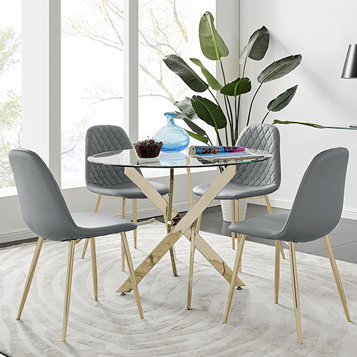A round clear glass dining table with gold metal starburst nested legs, and 4 grey faux-leather Corona dining chairs, also with gold legs.