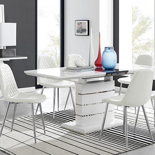 The image shows a white high gloss rectangular dining table with a structural stacked blocks plinth base. Around the table are 4 white faux-leather dining chairs with silver legs.