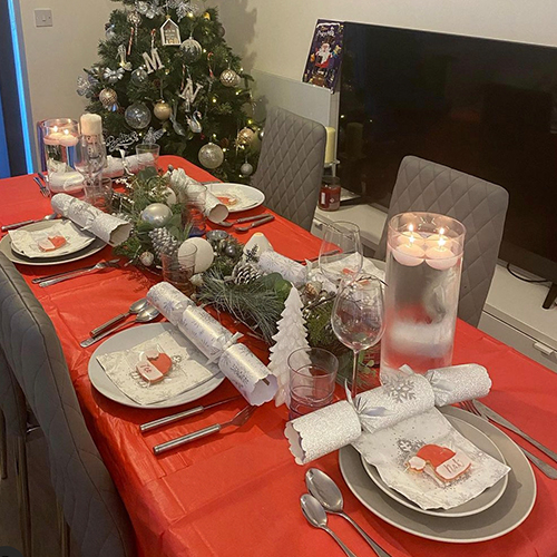 Instagram Christmas inspiration - modern dining area with red tablecloth, and green fir tree bough garland with baubles
