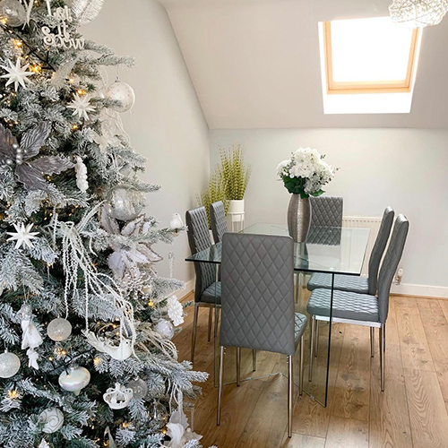 modern dining area with Christmas decorations around and on table.