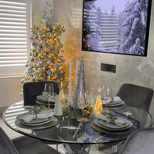 modern dining table with small silver, white and gold decorative christmas trees in the centre