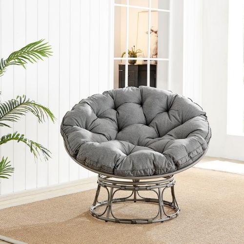 grey rattan moon chair with grey cusions, pictured in bright sunny conservaotry with greenery and beige rug