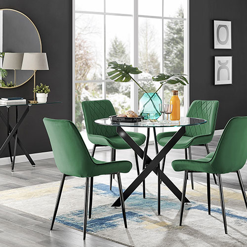 Round glass dining table with black metal nested legs and 4 green velvet dining chairs with black legs