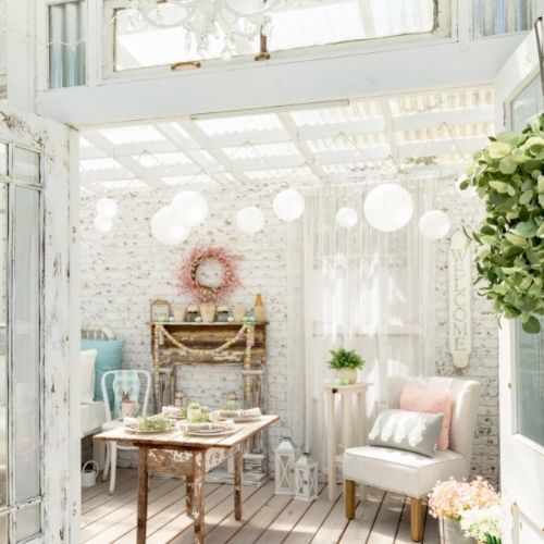 shabby chic dining room with rustic table, white bleached wood and exposed brickwork, white paper lanterns and soft pastel shade accessories