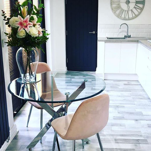 round dining table, with 2 blush pink-beige velvet chairs an large vase of stargazer lillies.