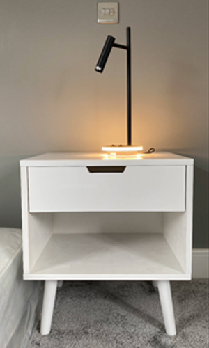 A black orbit lamp on a white gloss bedside table