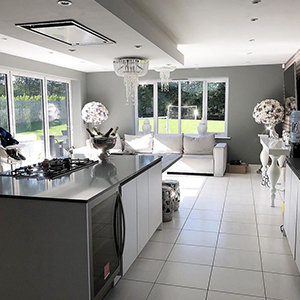 image of Danielle Lloyd's open plan kitchen featuring a central island with hob, and table area, with sofa and living area at far end. home renovation through open plan living