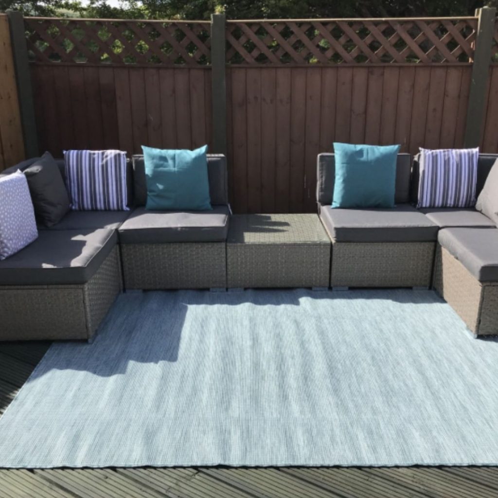 brown rattan garden set  - modular sofa with coffee table and brown cushions on decked area, with outdoor rug.