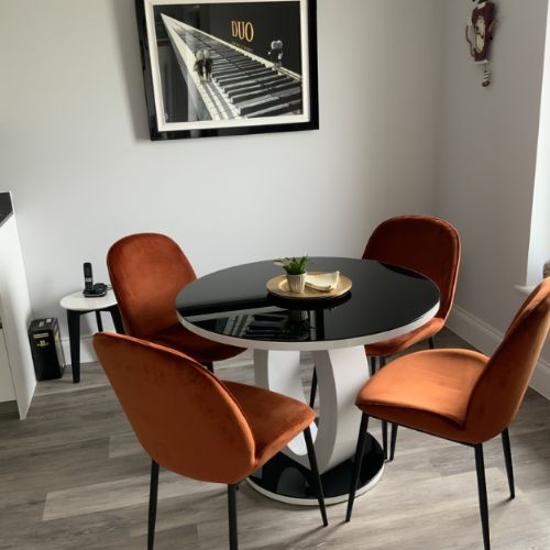white anbd black dining space with round high gloss black and white statement table with orange velevet chairs