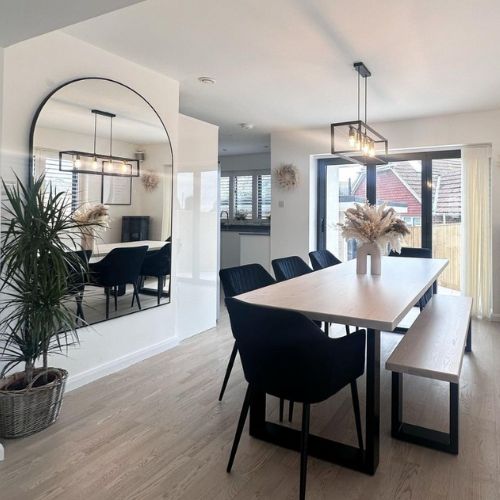 Industrial chic dining area with wood and metal dining table and bench, and black velvet tub dining chairs, with industrial light fixing nad large wall mirror. 