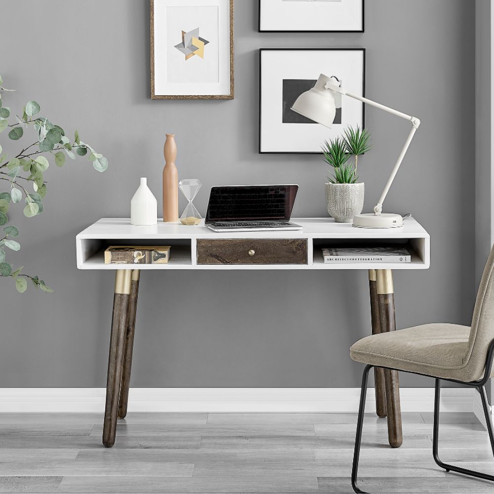 modern scandi minimamilst desk in white wood with dark wood central drawer and wooden tpered legs with gold accents. A laptop, angle poise lamp and some accessories decorate the desk top.