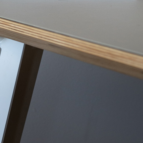 close up of edge of wooden table, with grey vinyl table protector overlaid on it.