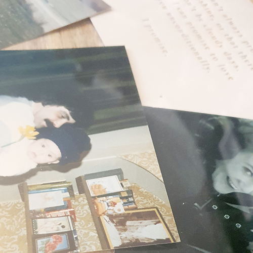 side-on close up view of photos and cards under glass table protector surface, showing how the table topper can also be used to display mementos.