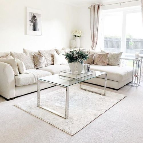 bright modern living room with large corner sofa and rectangular glass coffee table with minimalist square leg frames.