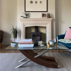 stone fireplace with black metal burner, with wood and chrome glass-topped coffee table