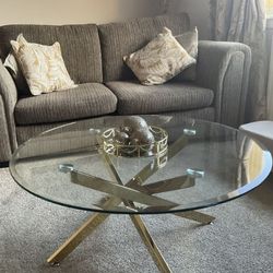 grey sofa and carpet with round glass nad gold coffee table